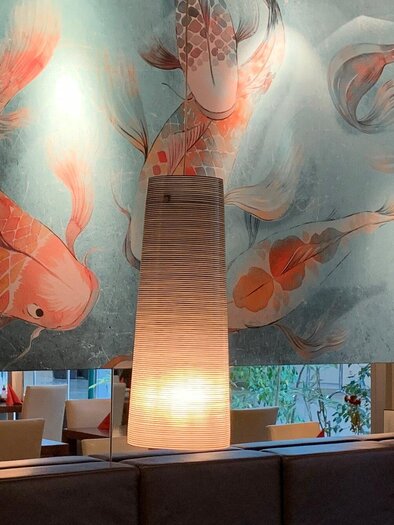 A stylish restaurant with a mural of koi fish. Two modern lamps provide a pleasant lighting. | © Pho You