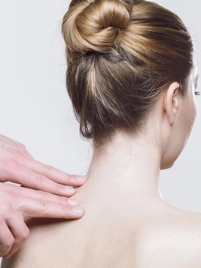 A person is receiving a massage in the neck area. In the background, a neutral, light wall can be seen. | © Symbolbild PixaBay