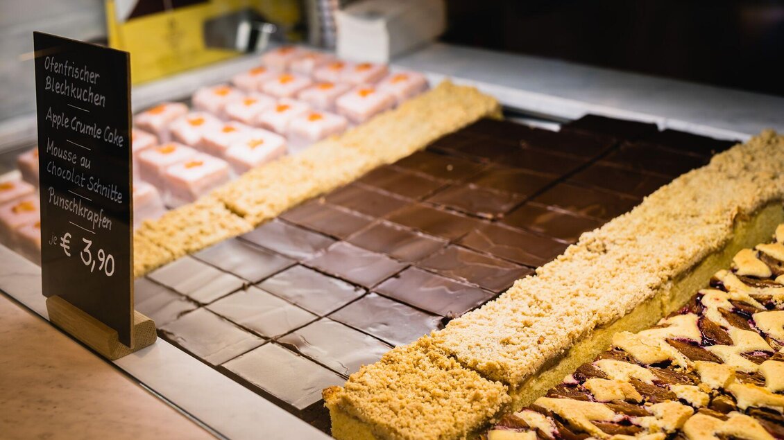 Eine Auswahl an köstlichen Kuchen und Desserts, darunter Schokoladen- und Mürbeteigvariationen. Im Vordergrund steht ein Preis von 3,90 € für die Leckereien. | © Pirker GmbH Mariazell