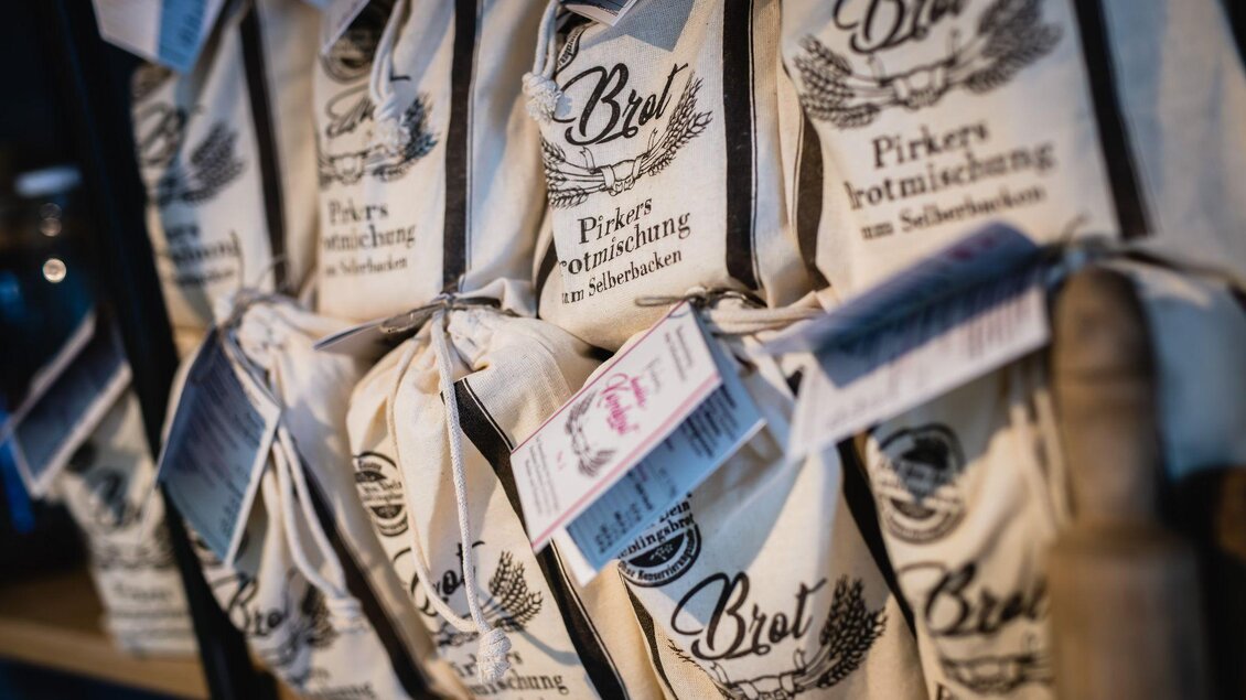 Eine Reihe von Päckchen mit Brotbackmischungen steht auf einem Regal. Die Verpackungen sind in naturbelassenem Design und tragen Schriftzüge. | © Pirker GmbH Mariazell