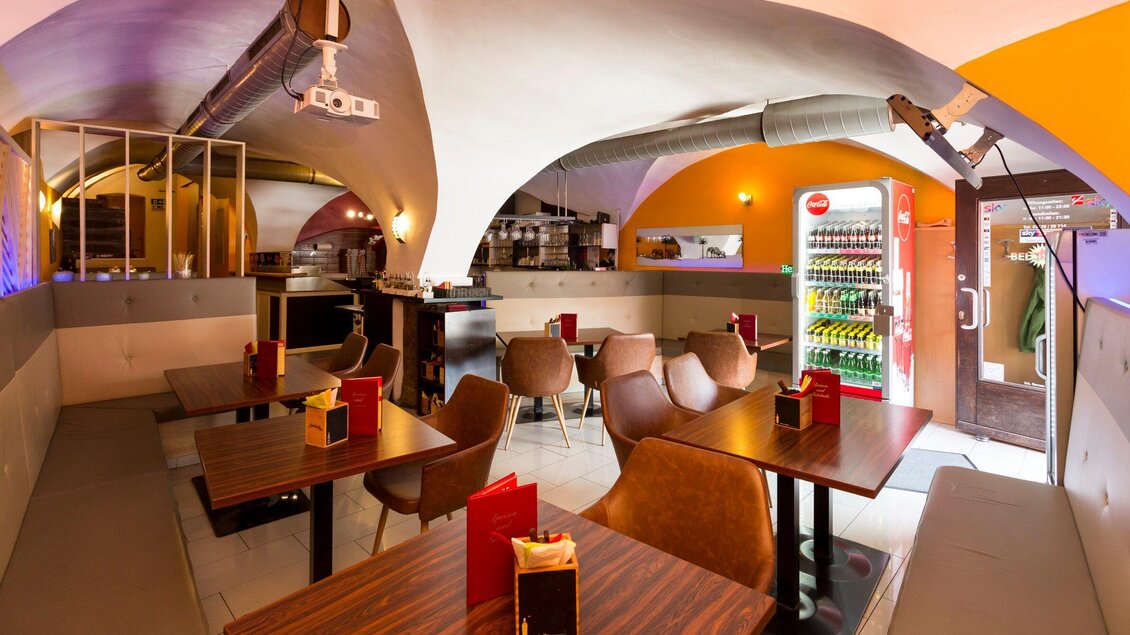Ein modernes Café mit gemütlichen Tischen und Stühlen. Die Wände sind in warmen Farben gehalten und es gibt eine Verkaufsmaschine im Hintergrund. | © TV Region Graz - René Vidalli