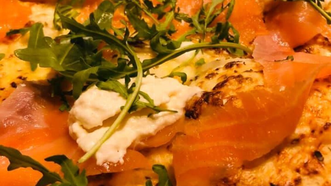Eine köstliche Pizza mit Räucherlachs, frischem Rucola und cremigem Käse. Die goldene Kruste ist perfekt gebacken. | © Pizzeria Fratelli