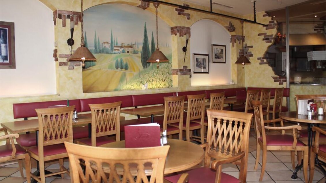 Ein gemütliches Restaurant mit hölzernen Möbeln und roten Sitzbänken. Die Wände sind in warmen Farbtönen gestaltet, mit einem großen Wandgemälde einer Landschaft. | © Pizzeria Fratelli