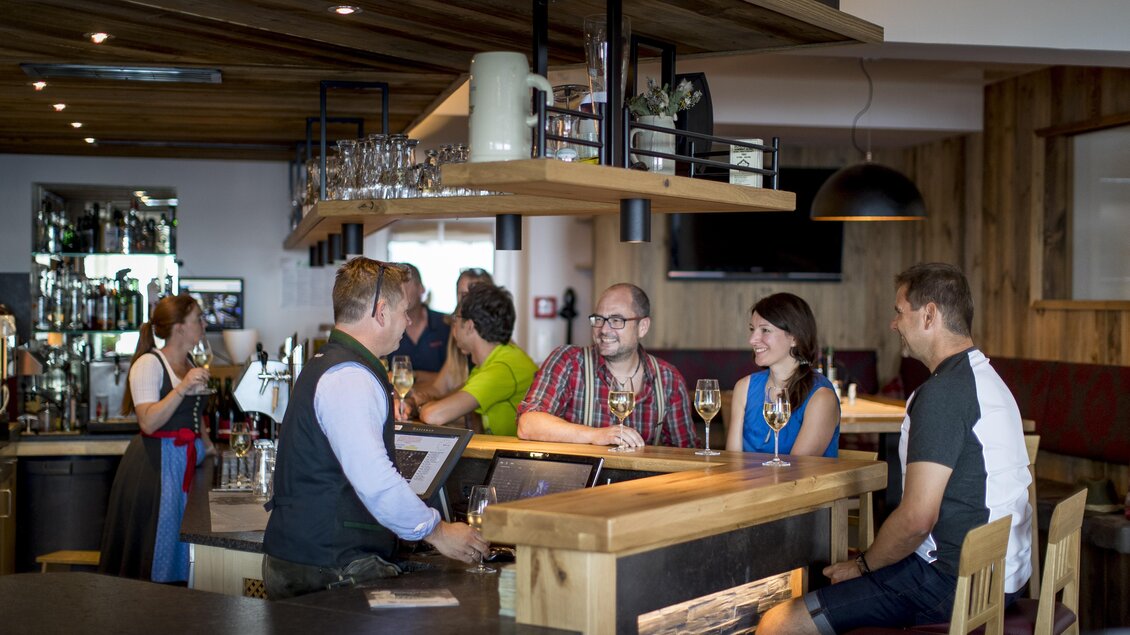 Eine gemütliche Bar mit Sitzplätzen und moderner Einrichtung. Gäste unterhalten sich und genießen Drinks in entspannter Atmosphäre. | © Tom Lamm