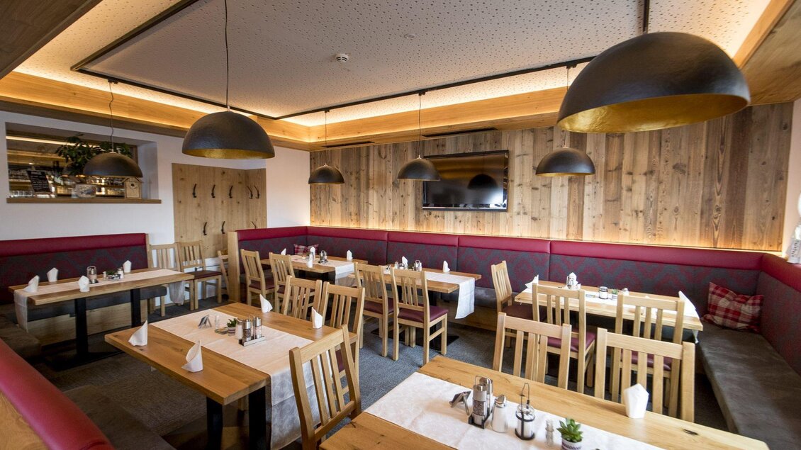 Ein gemütliches Restaurant mit Holzdekor und sanfter Beleuchtung. Die Tische sind ordentlich gedeckt und laden zum Verweilen ein. | © Planaihof, Tom Lamm