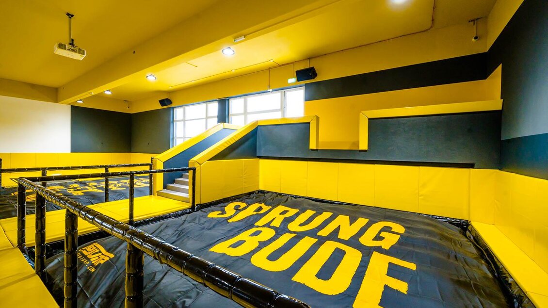 Ein Trampolinhallenbereich mit gelben Wänden und einem großen Sprungbereich. Die Anlage bietet eine sichere Umgebung für Sprünge und akrobatische Übungen. | © Playworld Spielberg