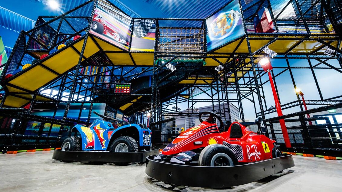 Ein aufregender Karrenspaß in einer Indoor-Arena mit zwei bunten Karts. Der Bereich hat eine spannende Spielstruktur im Hintergrund. | © Playworld Spielberg