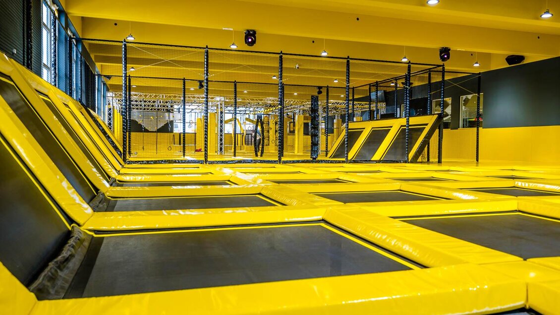 Eine Trampolinhalle mit vielen gelben Trampolinen und einer modernen Umgebung. Das bunte Design schafft eine einladende Atmosphäre für Spaß und Aktivität. | © Playworld Spielberg
