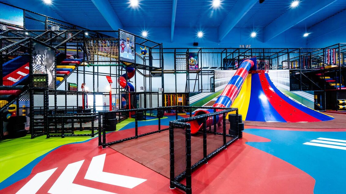 Ein farbenfroher Spielplatz mit einem großen Klettergerüst und einer Riesenrutsche. Der Boden ist bunt gestaltet und lädt zum Spielen ein. | © Playworld Spielberg