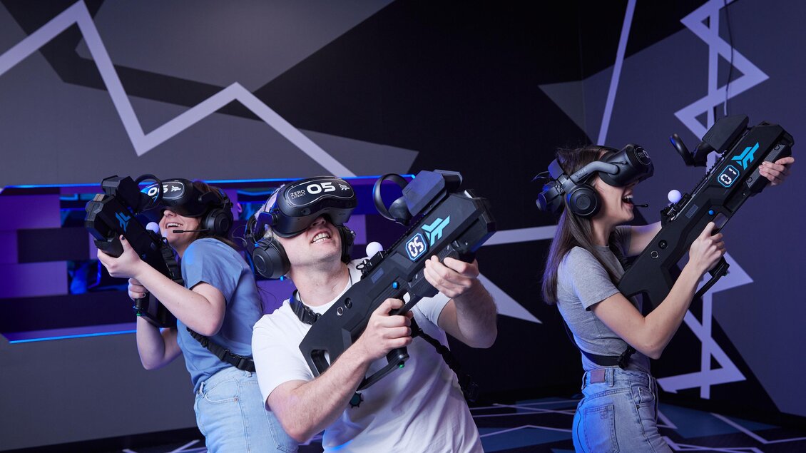Drei Personen tragen VR-Headsets und halten futuristische Spielgeräte. Sie scheinen in ein aufregendes Virtual-Reality-Spiel vertieft zu sein. | © Playworld Spielberg