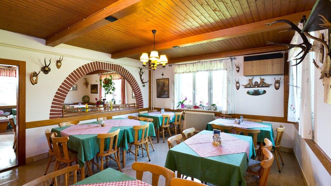Ein gemütliches Restaurant mit Holztischen und Stühlen. Die Wände sind dekoriert und es gibt große Fenster, die viel Licht hereinlassen. | © TV Region Graz - René Vidalli
