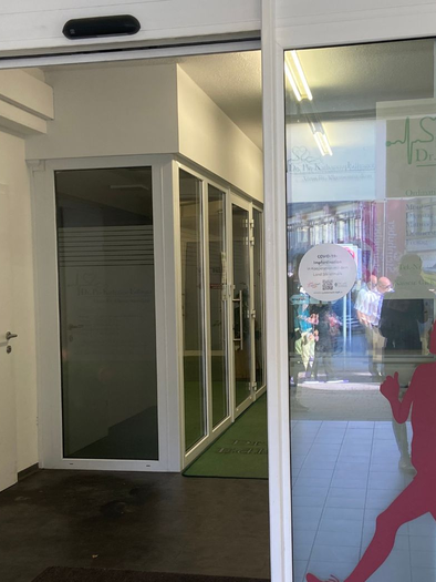 Ein Eingang zu einem Fitnessstudio mit silbernen Wänden und großen Fenstern. Auf den Türen sind stilisierte Silhouetten von Sportlern zu sehen. | © TVB Ausseerland-Salzkammergut/Jana Grill