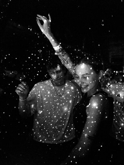 Black-and-white capture of people dancing in a dark room, surrounded by points of light that resemble stars in the space. | © Postgarage - Stefan Leitner
