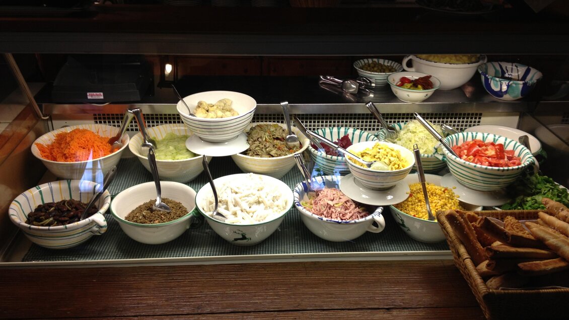 Ein Buffetschrank mit verschiedenen Schalen voller frischer Zutaten. Zu sehen sind bunte Gemüse- und Salatbeilagen sowie Brot. | © Postillions Einkehr