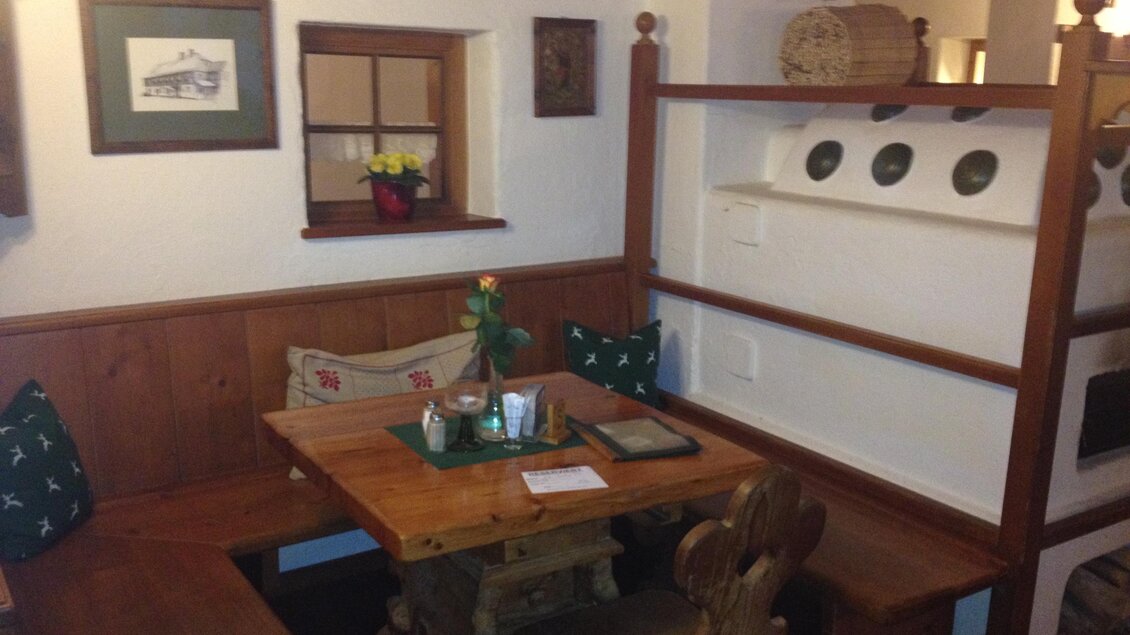 Ein gemütlicher Essbereich mit Holzmöbeln und traditionellen Dekorationen. Die Wände sind mit Bildern und Tellern geschmückt. | © Postillions Einkehr