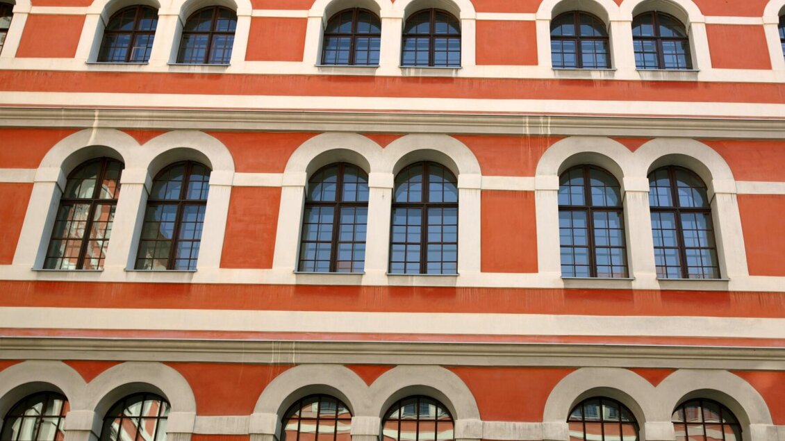 Nahaufnahme der roten Außenfassade mit weißen Rundbogenfenstern am Priesterseminar Graz. | © Graz Tourismus-Harry Schiffer