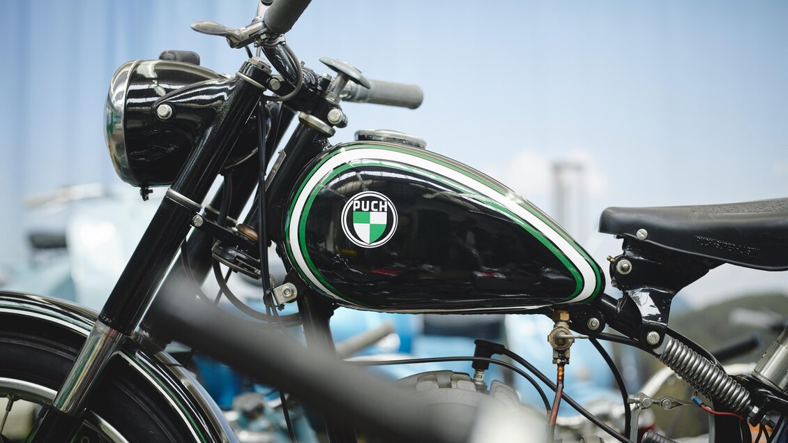 Ein vintage Motorrad mit schwarzem Lack und grünen Akzenten. Das Bild zeigt den Tank und das Lenkrad des Fahrzeugs. | © Königshofer