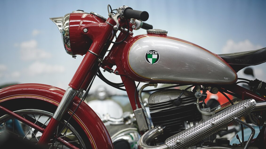 Ein klassisches Motorrad in Rot und Silber. Es hat einen eleganten Look und ist detailreich gestaltet. | © Königshofer