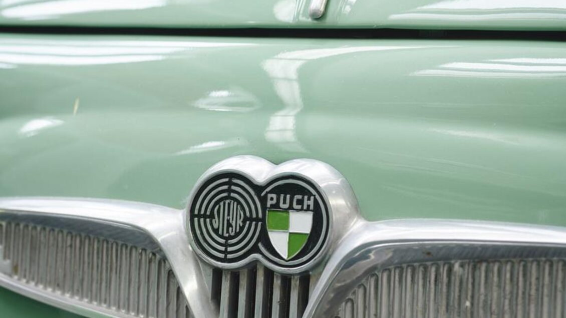 Ein klassisches Auto in einem sanften Grünton mit einem glänzenden Kühlergrill. Das Logo von Puch ist deutlich sichtbar. | © Königshofer