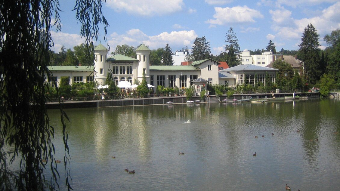 Ein malerischer See mit einem schönen Gebäude im Hintergrund. Die Umgebung ist grün und einladend, ideal für Entspannung. | © Purberg