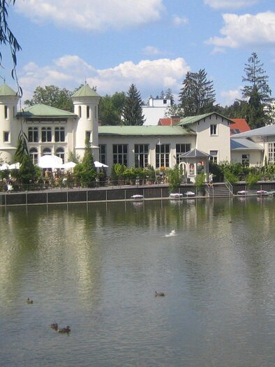 A picturesque lake with a beautiful building in the background. The surroundings are green and inviting, ideal for relaxation. | © Purberg