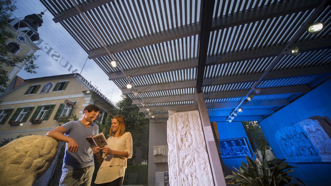 Zwei Personen stehen in einem modernen Ausstellungsraum und betrachten ein Buch. Im Hintergrund sind Skulpturen und eine helle, einladende Architektur zu sehen. | © Bernhard Bergmann