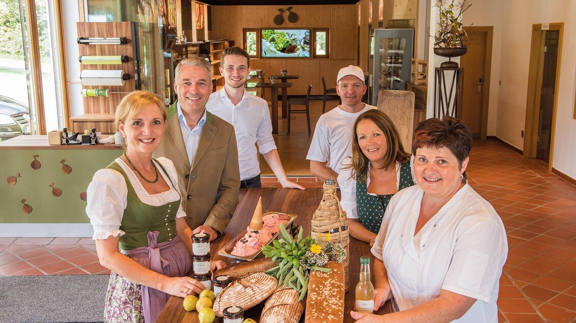 Eine Gruppe von fünf Personen steht in einem gemütlichen Raum und präsentiert verschiedene Lebensmittel, darunter Brot und Obst. Die Atmosphäre ist freundlich und einladend. | © Helmut Schweighofer