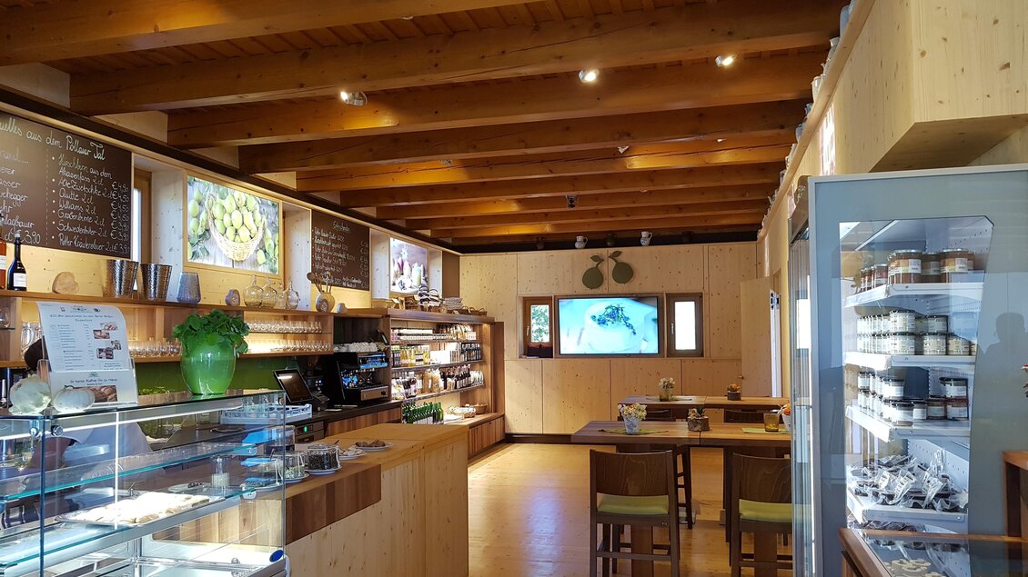 Ein gemütliches Café mit Holzverkleidung und Regalen voller Produkte. Es gibt einen Tresen mit einer großen Auswahl an Leckereien und Tischen zum Sitzen. | © Tourismusverband Oststeiermark