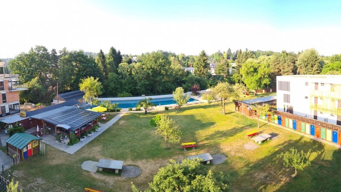 Im Ragnitzbad ist ausreichend Grünfläche zum Entspannen. Neben dem Pool gibt es Sitzgelegenheiten und einige farbenfrohe Kabinnen. | © Ragnitzbad