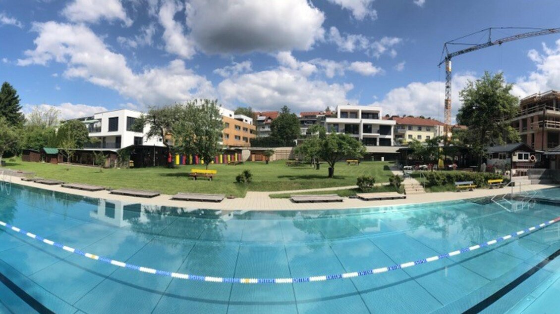 Schwimmbahnen sind ein fester Bestandteil im Ragnitzbad in Graz, mit großzügigen Grünflächen im Hintergrund. Wolken und Bäume verleihen dem Ort eine entspannte Atmosphäre. | © Ragnitzbad