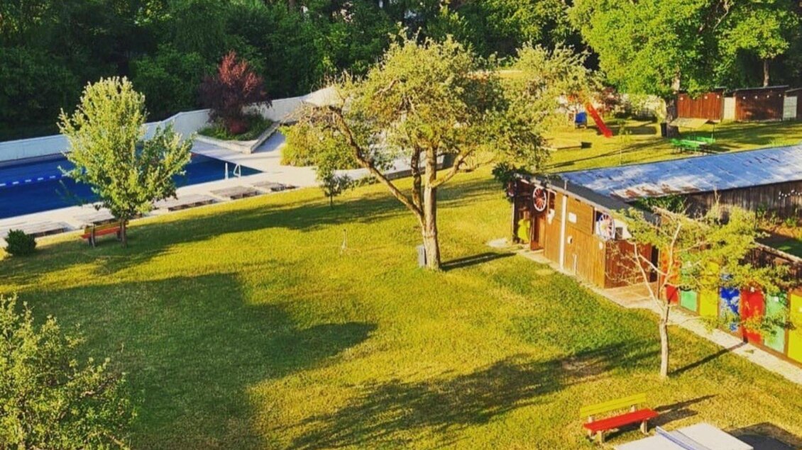 Mit bunten Kabinnen und der großen Grünfläche mit Bäumen ist das Ragnitzbad ein beliegter Treffpunkt in Graz.  | © Ragnitzbad