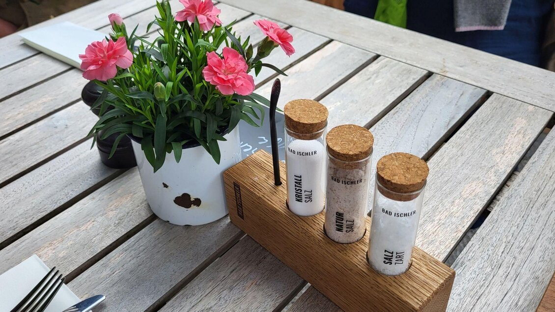 Ein hübsches Tischarrangement mit bunten Nelken in einem weißen Blumtopf. Auf dem Tisch stehen drei kleine Gläser mit verschiedenen Gewürzen in einem Holzständer. | © Petra Kirchschlager