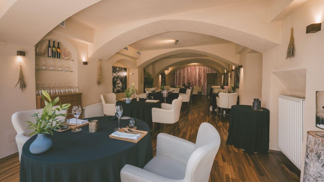 Ein elegantes Restaurant mit hellen Wänden und Holzböden. Die Tische sind mit dunklen Tüchern gedeckt und es gibt bequeme Stühle. | © Artis