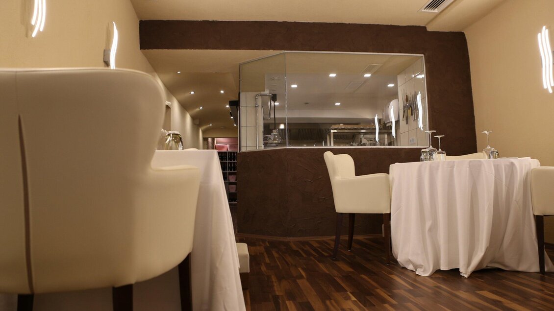 Ein elegantes Restaurant mit Tischen und weißen Tischdecken. Die Wände sind in warmen Tönen gehalten und die Beleuchtung ist sanft. | © Artis