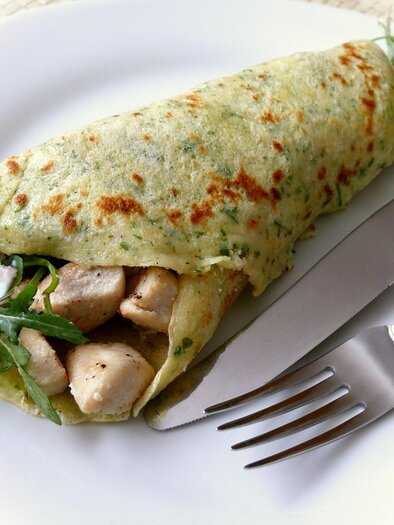 A stuffed omelette with chicken pieces and arugula on a white plate. Cutlery is next to the omelette. | © Kastanienlaube