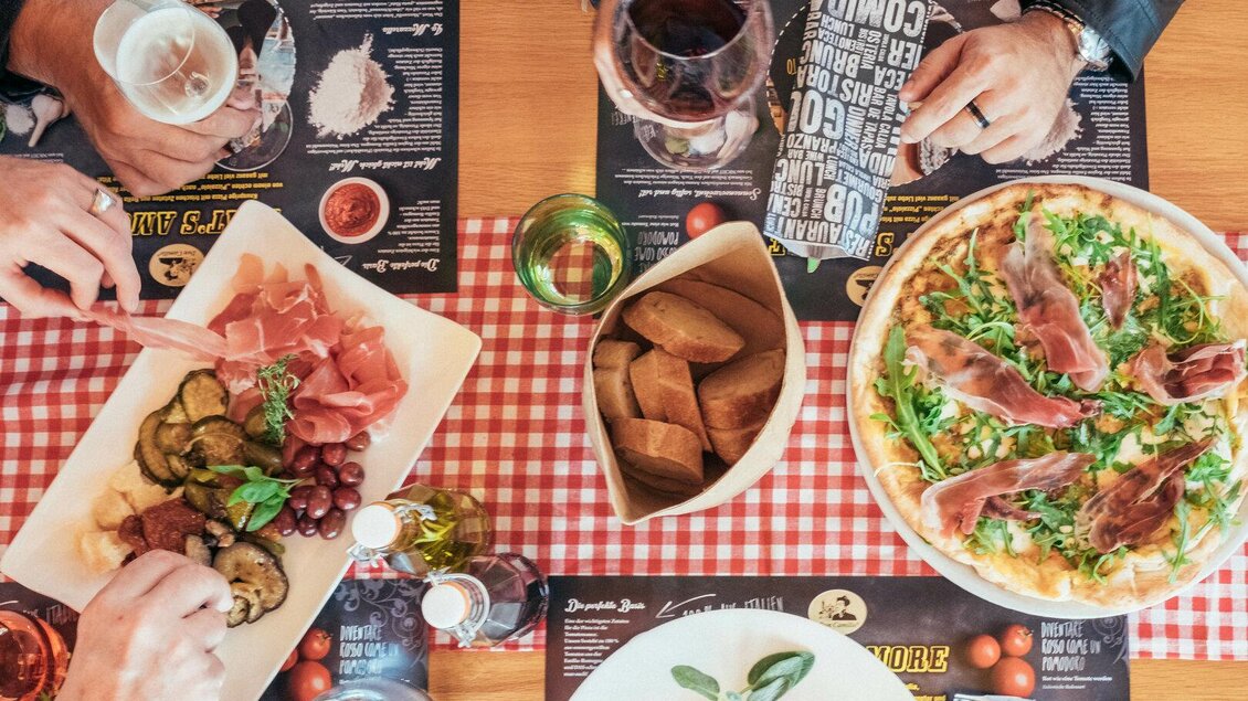 Ein Tisch mit verschiedenen italienischen Gerichten, darunter Pizza und Vorspeisen. Die Atmosphäre ist gemütlich und einladend. | © Thermenresort Loipersdorf