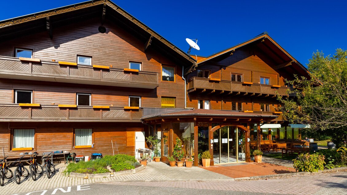 Ein gemütliches Holzhaus mit einem einladenden Eingangsbereich. Fahrräder stehen bereit, und der Himmel ist klar und blau. | © Lipizzanerheimat-Schiffer