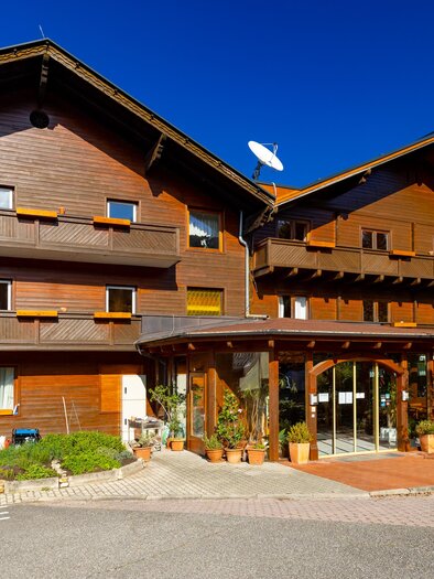 Ein gemütliches Holzhaus mit einem einladenden Eingangsbereich. Fahrräder stehen bereit, und der Himmel ist klar und blau. | © Lipizzanerheimat-Schiffer