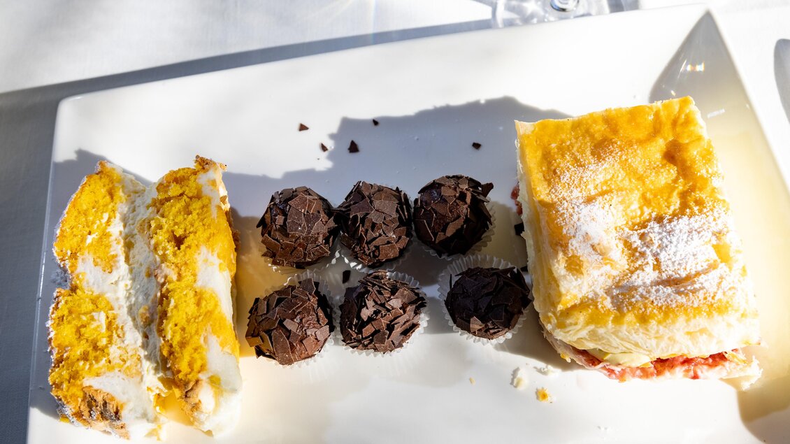 Ein Teller mit verschiedenen Desserts. Links ist ein Stück Torte und rechts ein Stück Gebäck, dazwischen sind kleine Schokoladenpralinen. | © Lipizzanerheimat-Schiffer