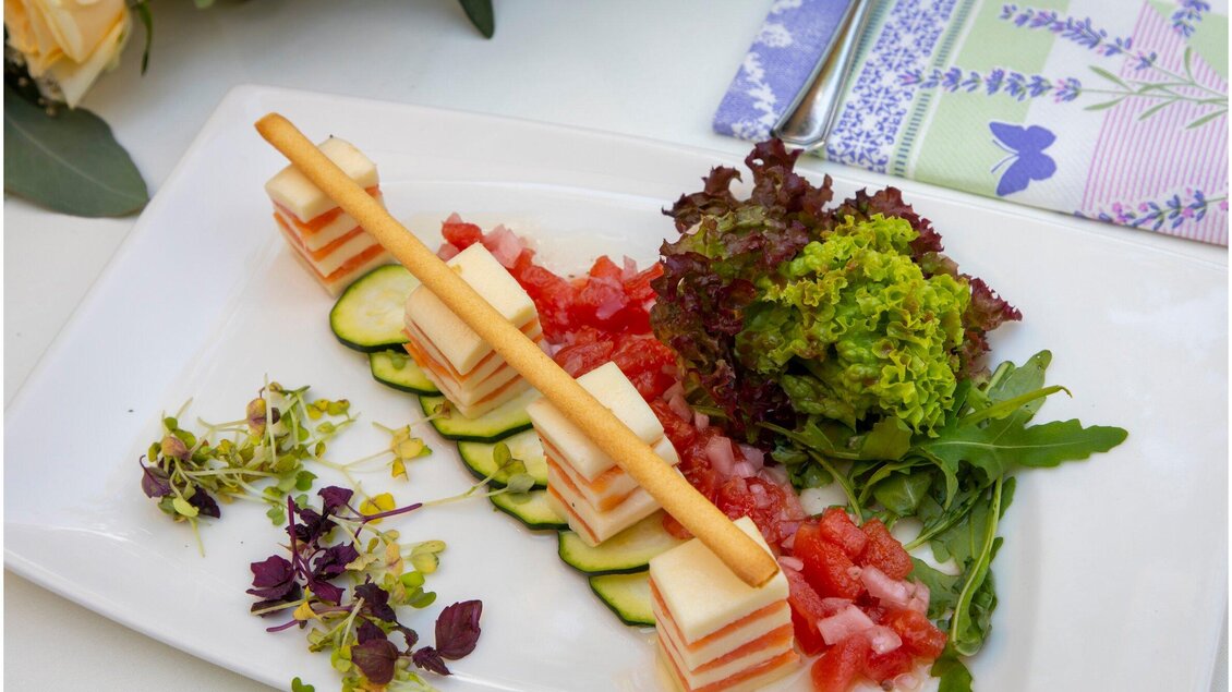 Ein kunstvoll angerichteter Gemüsesalat mit verschiedenen Farben. Er enthält Gurken, Tomaten, Blattsalat und essbare Blüten. | © TV Region Graz - Lunghammer