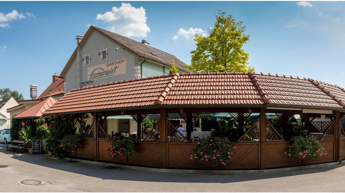 Ein gemütliches Restaurant mit einer überdachten Terrasse und bunten Blumen. Der Himmel ist klar und das Gebäude ist im traditionellen Stil gehalten. | © TV Region Graz - Lunghammer