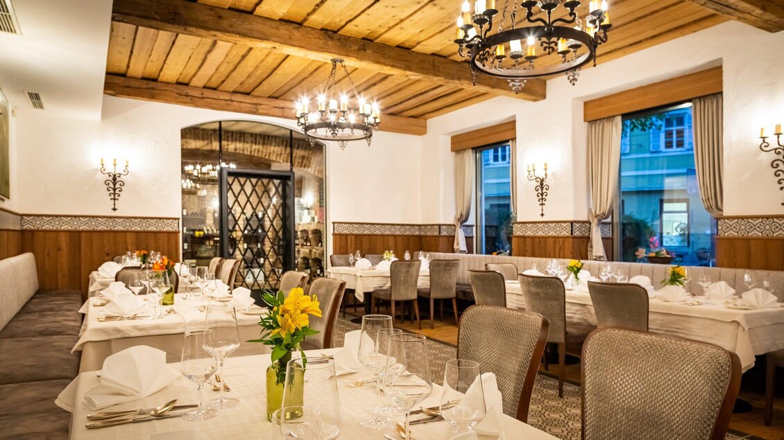 Ein elegantes Restaurant mit schön gedeckten Tischen und stilvollem Dekor. Die warme Beleuchtung und Holzbalken schaffen eine gemütliche Atmosphäre. | © Das Florian - Werner Krug