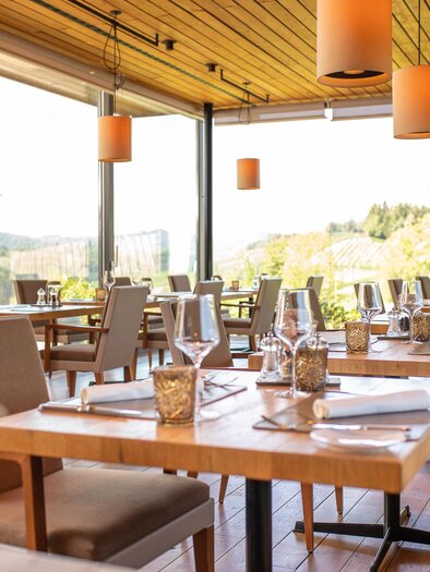 A modern restaurant with large windows and a view of nature. The tables are beautifully set and the lighting is warm and inviting. | © Regionalmanagement Südweststeiermark GmbH/webquart
