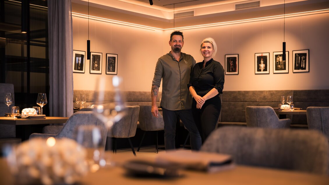 Ein modernes Restaurant mit stilvollem Design. Zwei Personen stehen lächelnd im Vordergrund. | © Nadine Geuter- Black Ink Production
