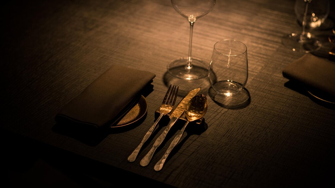 Ein eleganter Tisch mit Besteck, Gläsern und servierten Stofftaschentüchern. Die Atmosphäre ist gedämpft und stilvoll. | © Nadine Geuter - Black Ink Production