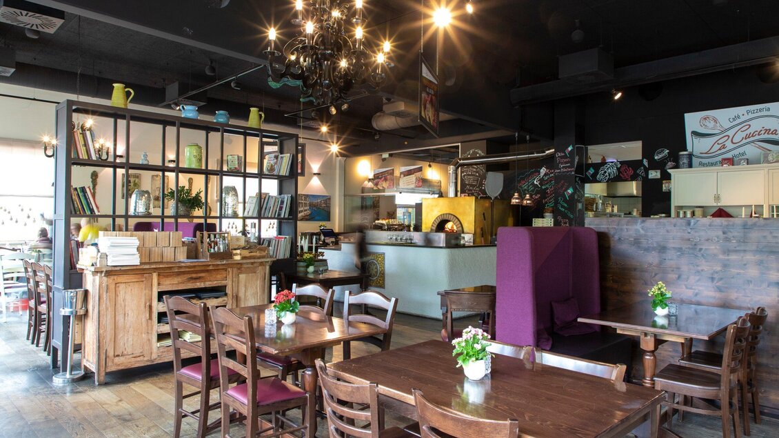 Ein gemütliches Café mit Holzstühlen und Tischen. Die Atmosphäre ist einladend mit dekorativen Pflanzen und einem offenenLayout. | © TV Region Graz - Lunghammer