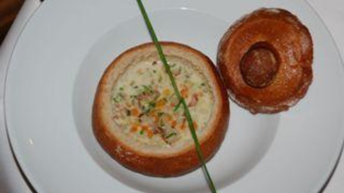 Eine kreative Speise in einem Brotbecher, gefüllt mit einer cremigen Mischung und Gemüse. Daneben befindet sich ein weiteres Brötchen. | © Restaurant Landhaus St. Georg