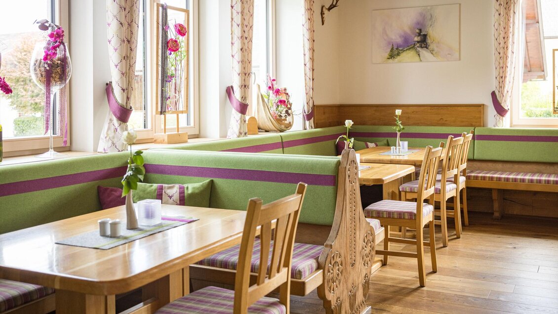 Ein gemütlicher Restaurantbereich mit Holztischen und bequemen Sitzgelegenheiten. Die Wände sind mit bunten Vorhängen und dekorativen Elementen geschmückt. | © Netzwerk Kulinarik wildbild