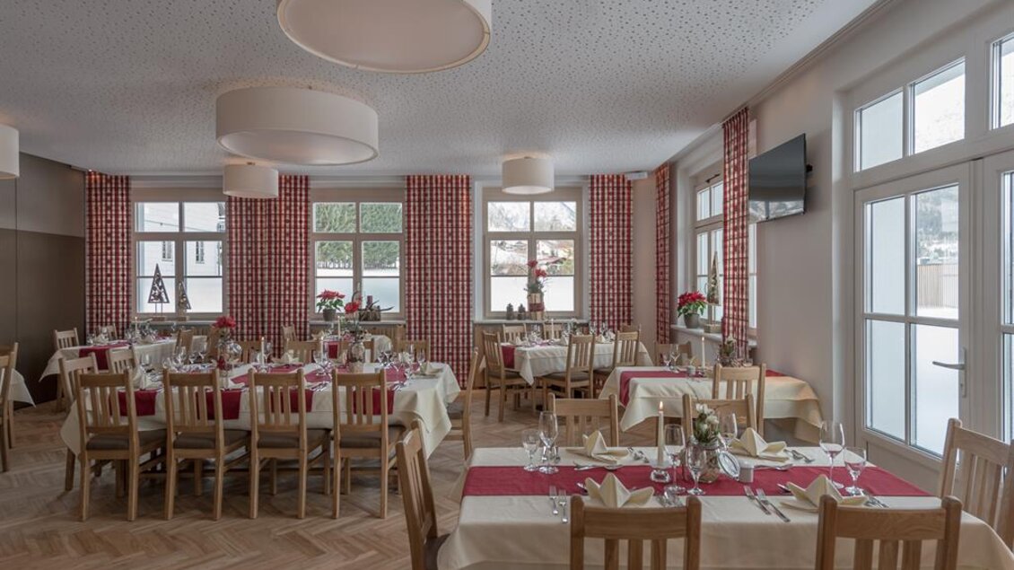 Ein einladendes Restaurant mit hellen Tischen und roten Tischdecken. Große Fenster lassen viel Licht herein und bieten einen Blick nach draußen. | © Restaurant Loy