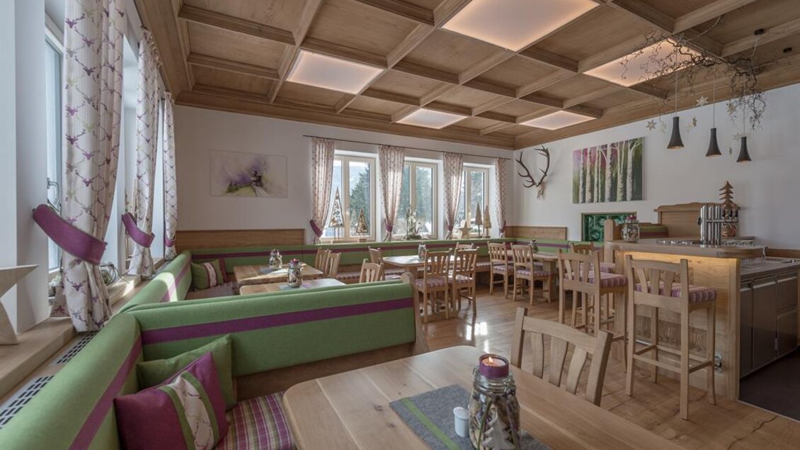Ein gemütliches Restaurant mit Holzdekor und großen Fenstern. Grüne Bänke und Holztische schaffen eine einladende Atmosphäre. | © Restaurant Loy